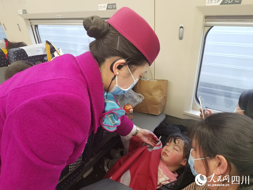G1983次列车上，金兰给睡熟的孩子盖上毛毯。人民网记者 郭莹摄